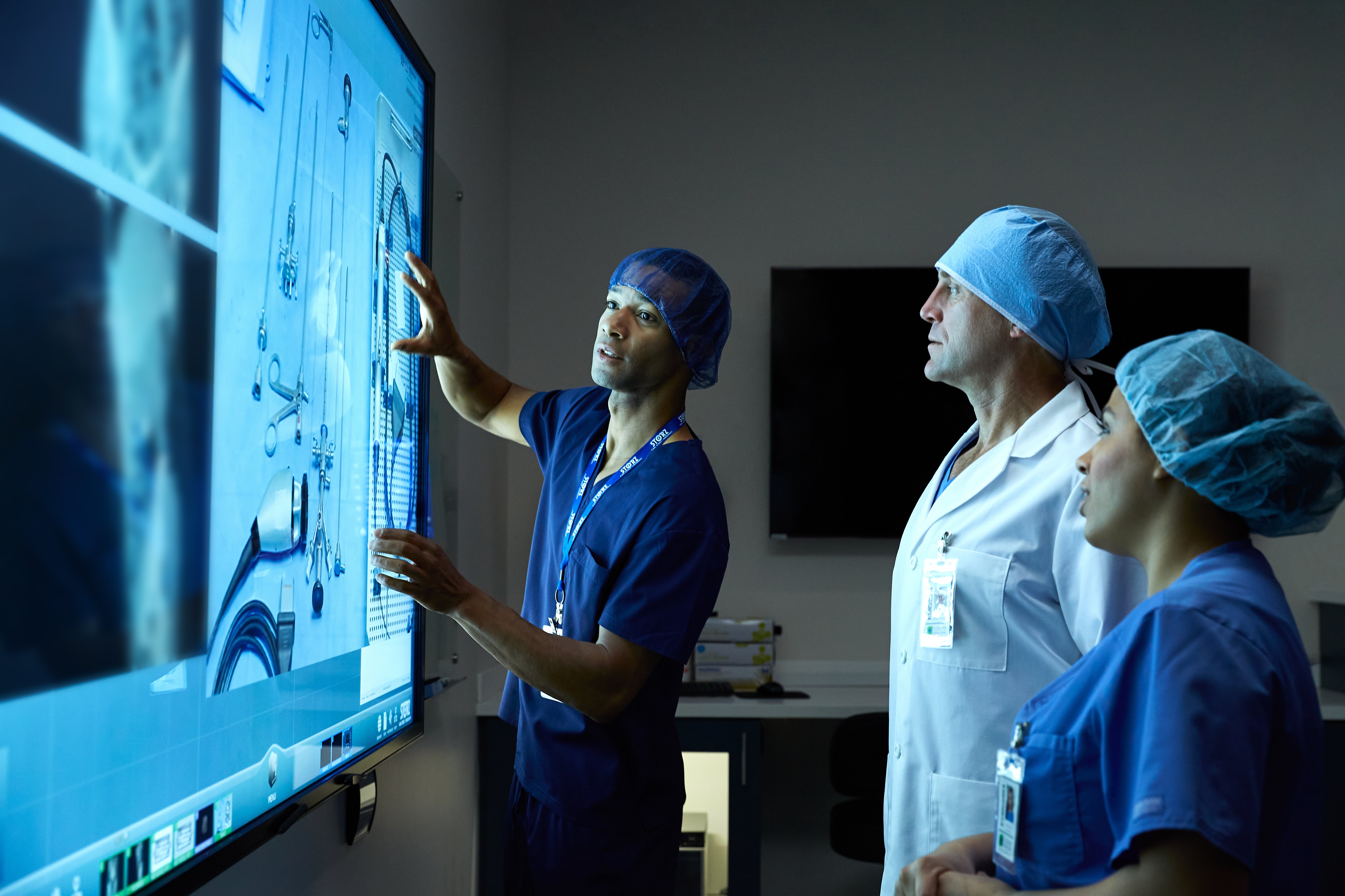 Medical professionals gather around a T1V KARL STORZ CollaboratOR touchscreen to view patient images and case details.